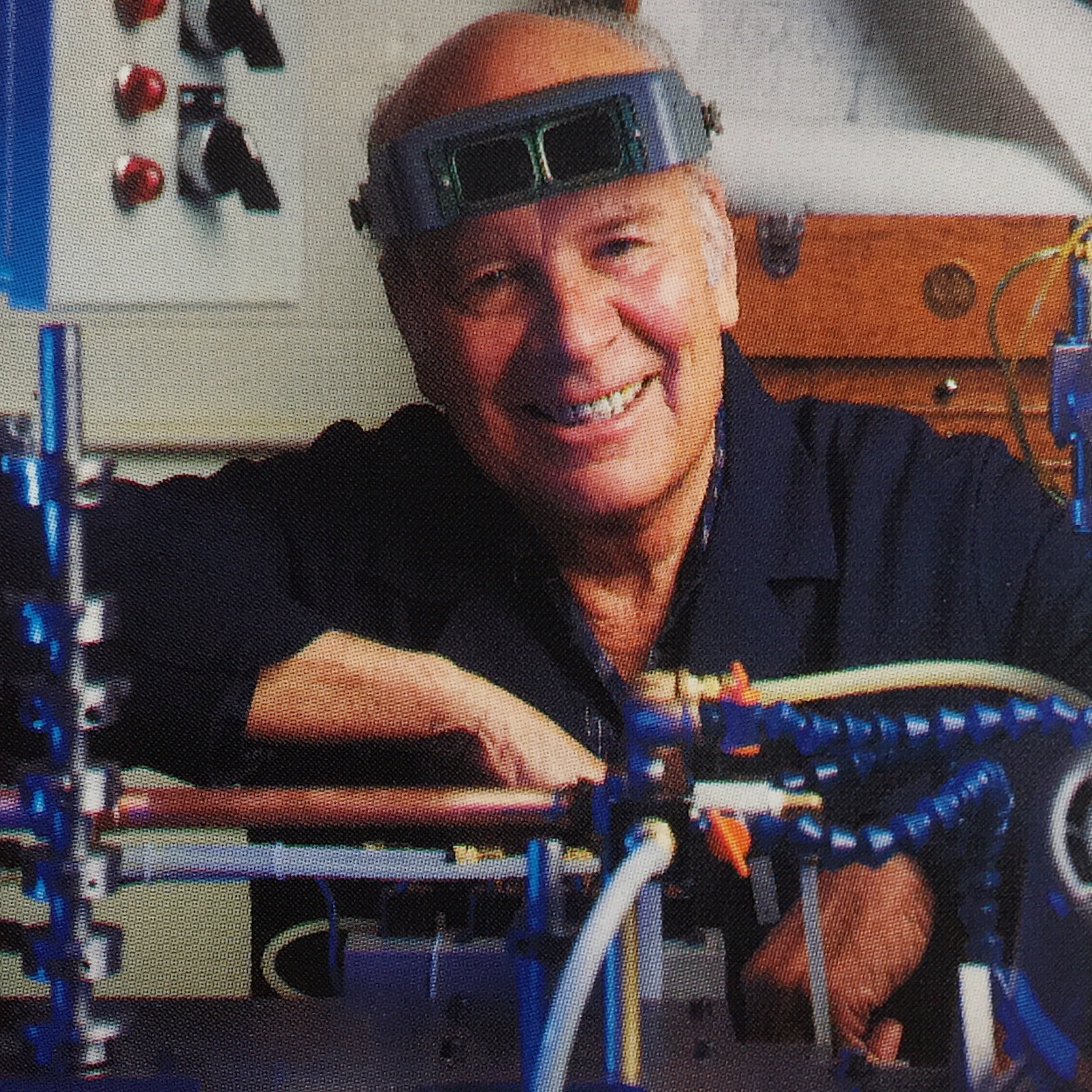 Derrick Perkins Sr. smiling beside machinery in the workshop